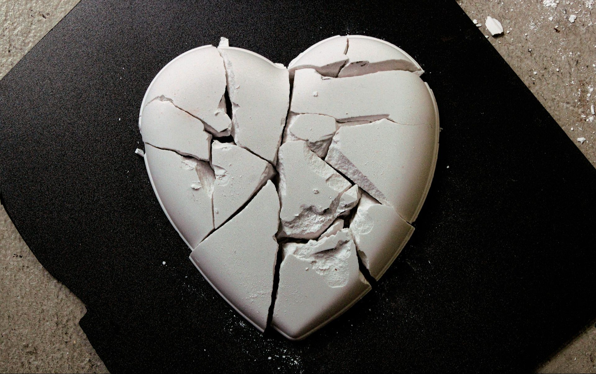 A broken heart-shaped object lying on a dark surface, representing emotional pain, heartbreak, and the process of healing and rebuilding self-worth.