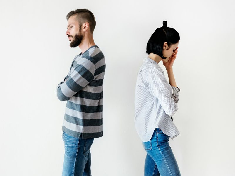 A couple standing back-to-back after an argument, symbolising relationship conflict, emotional distance, and the need for better communication and understanding.