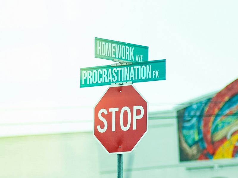 Street signs showing Homework Avenue and Procrastination Park above a stop sign, symbolising the need to stop procrastination and regain focus — Retrained Minds Hypnotherapy.