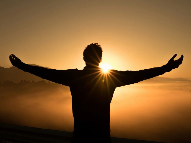 Silhouette of a person standing with open arms at sunrise, symbolising freedom, self-acceptance, and emotional renewal through personal growth.