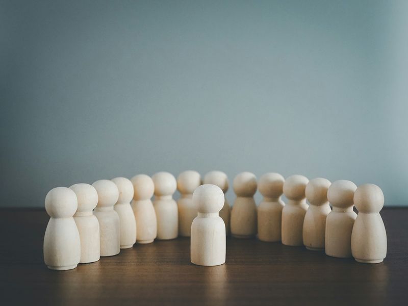 Wooden figures symbolising a confident presenter standing in front of a group, representing leadership, communication, and performance confidence.