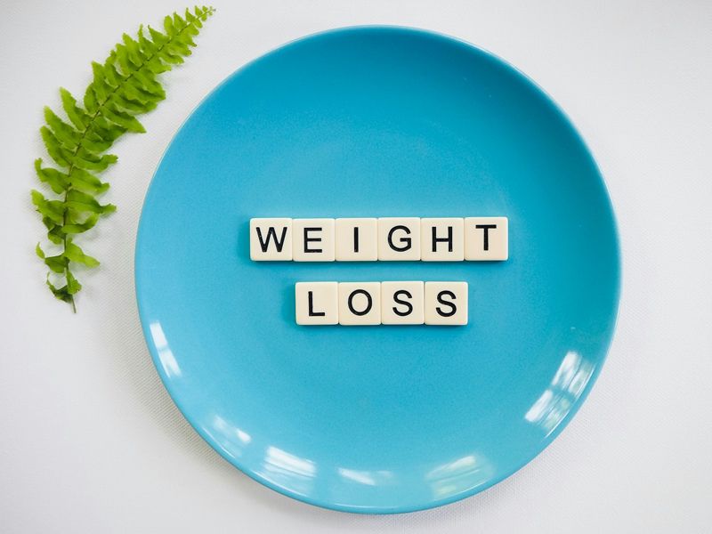 Blue plate with letter tiles spelling ‘Weight Loss’, symbolising clarity, focus, and the journey towards healthy habits - Retrained Minds Hypnotherapy.