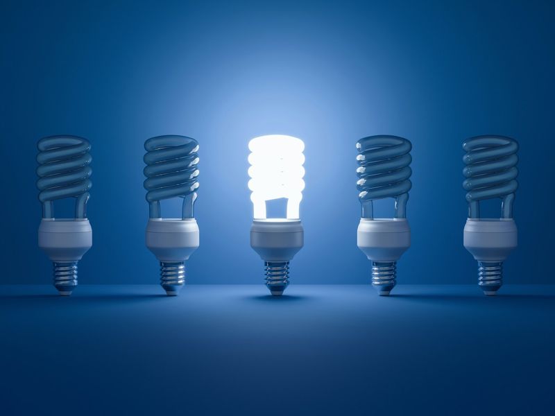 A single glowing lightbulb stands out brightly among several unlit bulbs, symbolising clarity, insight, and transformation - representing the power of new thinking and mental retraining.