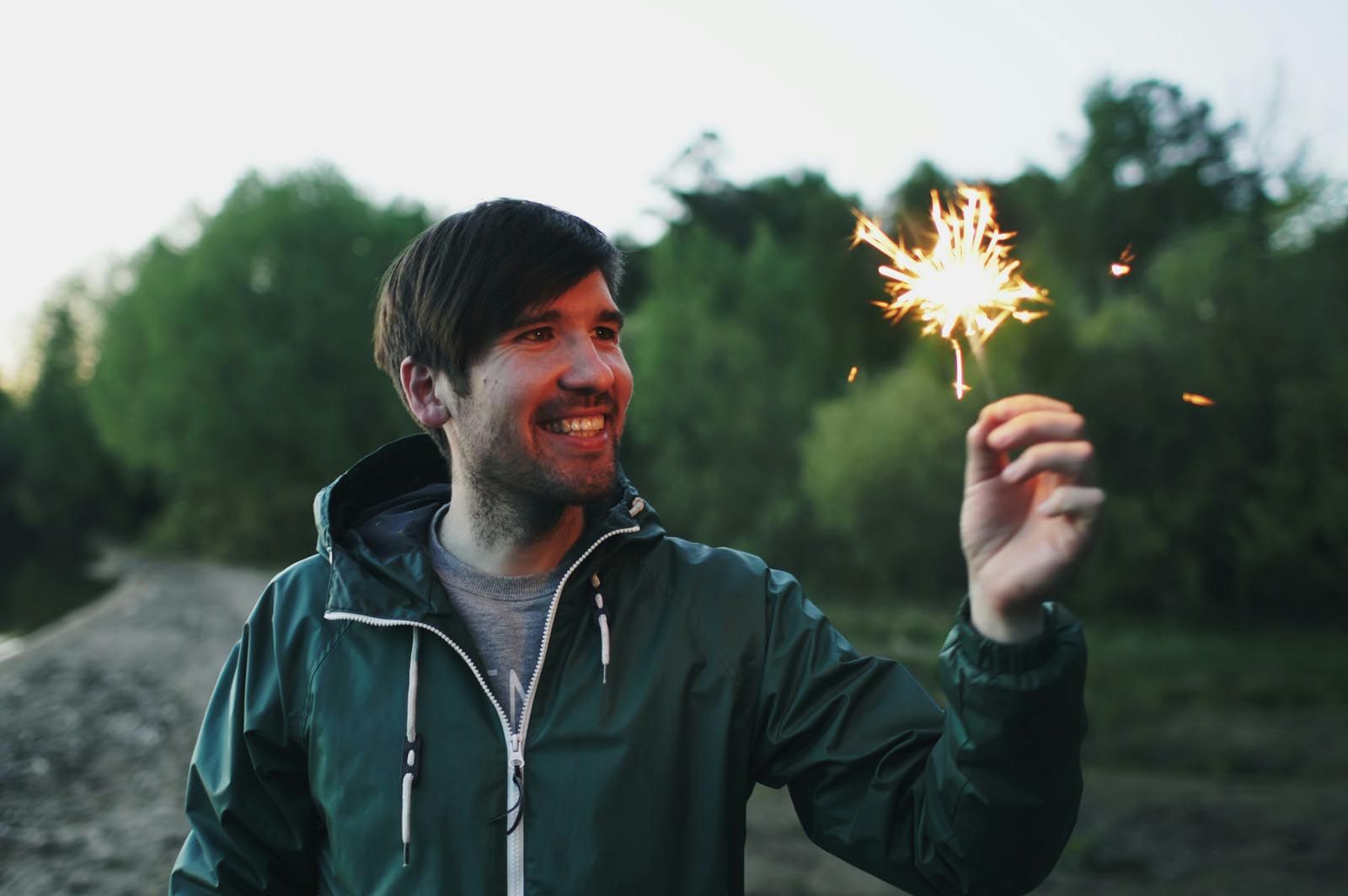 Smiling person holding a sparkler outdoors, symbolising joy, freedom, and positive transformation with Retrained Minds Hypnotherapy