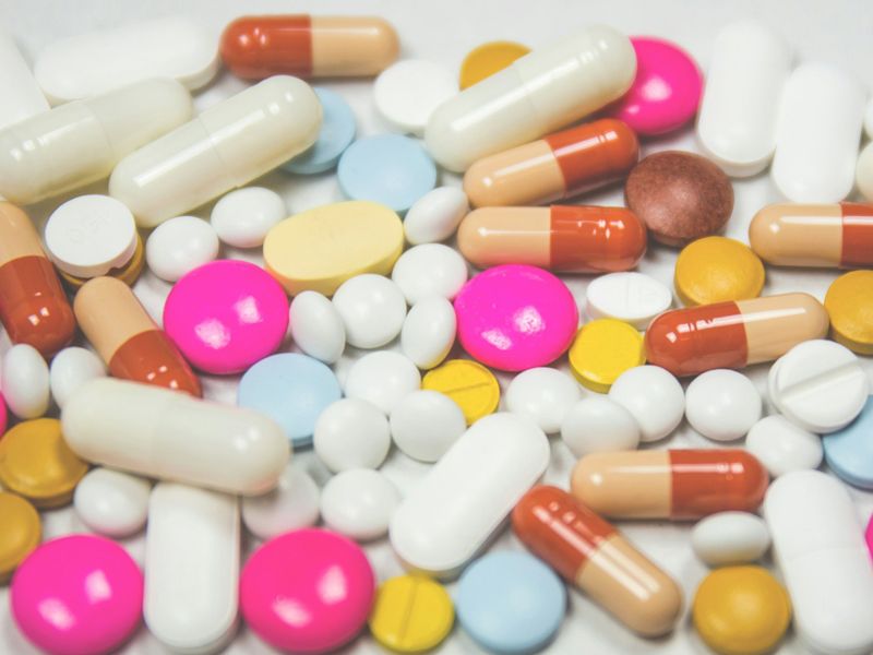A scattered collection of colourful pills and capsules symbolising dependence on medication and the journey towards natural healing through hypnotherapy.