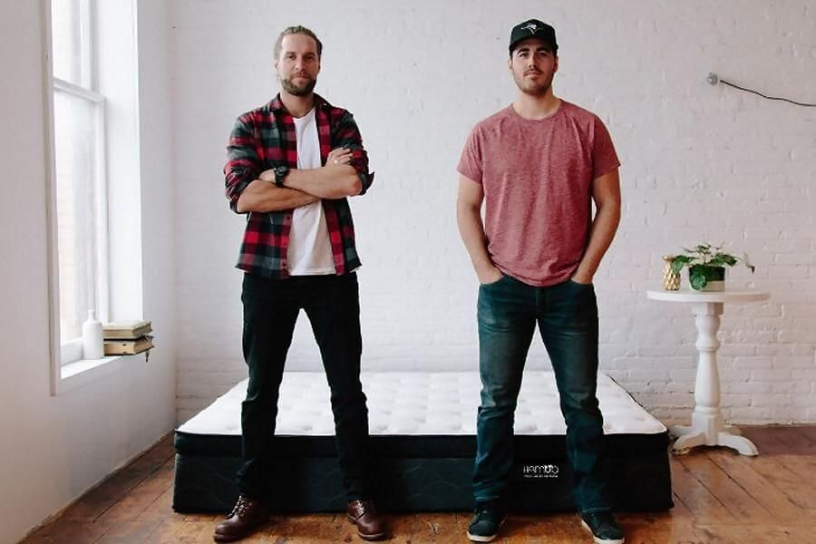 Stacks of white rectangular boxes labeled “Hammoq” stored on the floor beneath a metal warehouse shelving unit. The boxes are sealed and organized neatly, with visible blue branding and lines on the packaging.