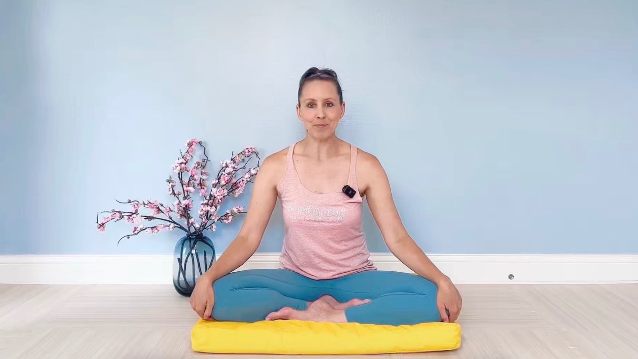 Asian woman meditating in living room—part of the Mindfulness & Meditation Course in the Complete Wellness Bundle.