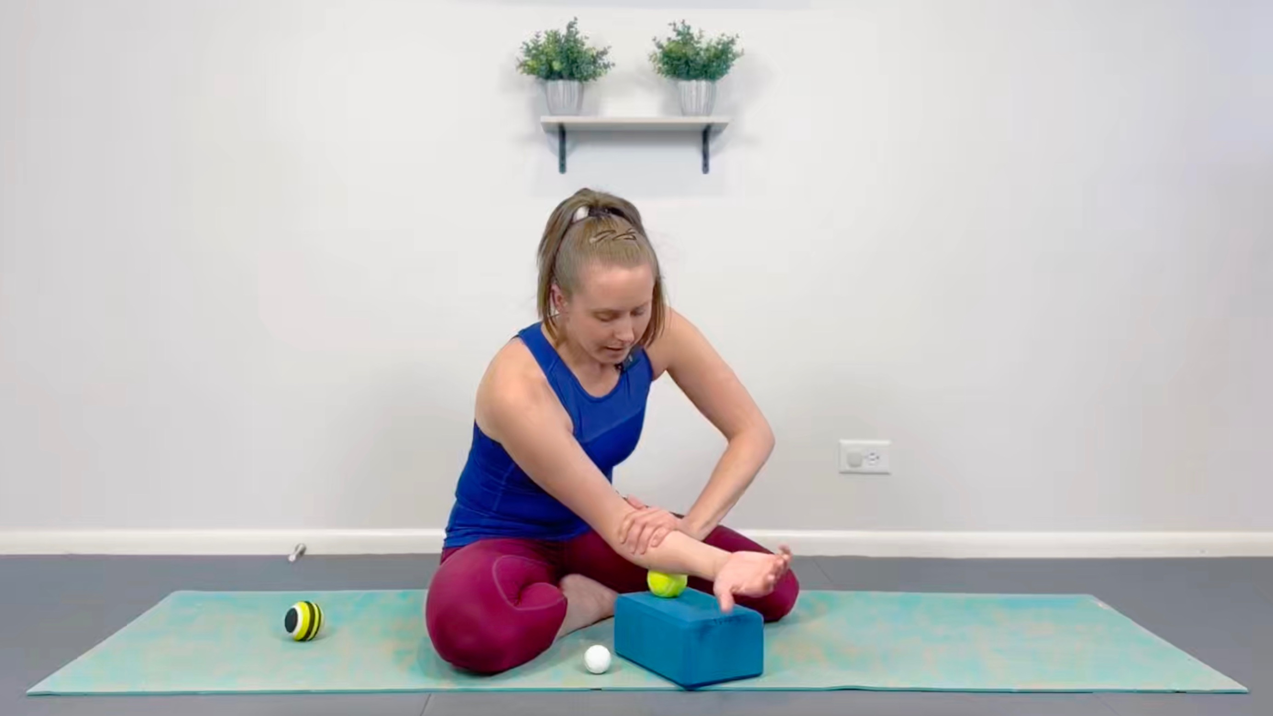 Woman on kneeling on yoga mat with a ball ready to roll to Foam Rolling Level 2 Mastercourse.
