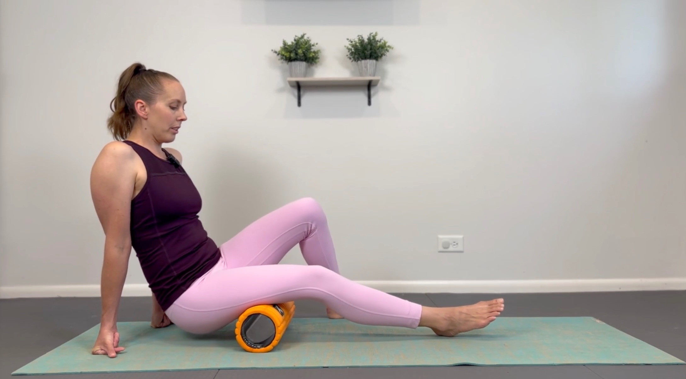 Woman on a yoga mat foam rolling her calves for the Foam Rolling Mastery Bundle.