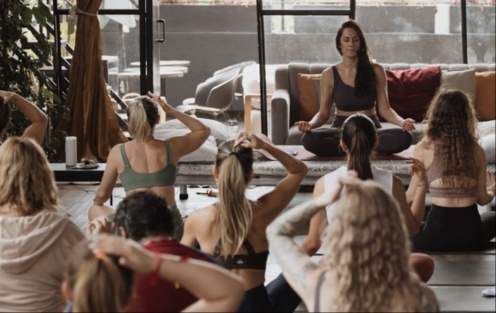 Varias personas sentadas en el piso en la clase de Emotions in Motion guiadas por Belu