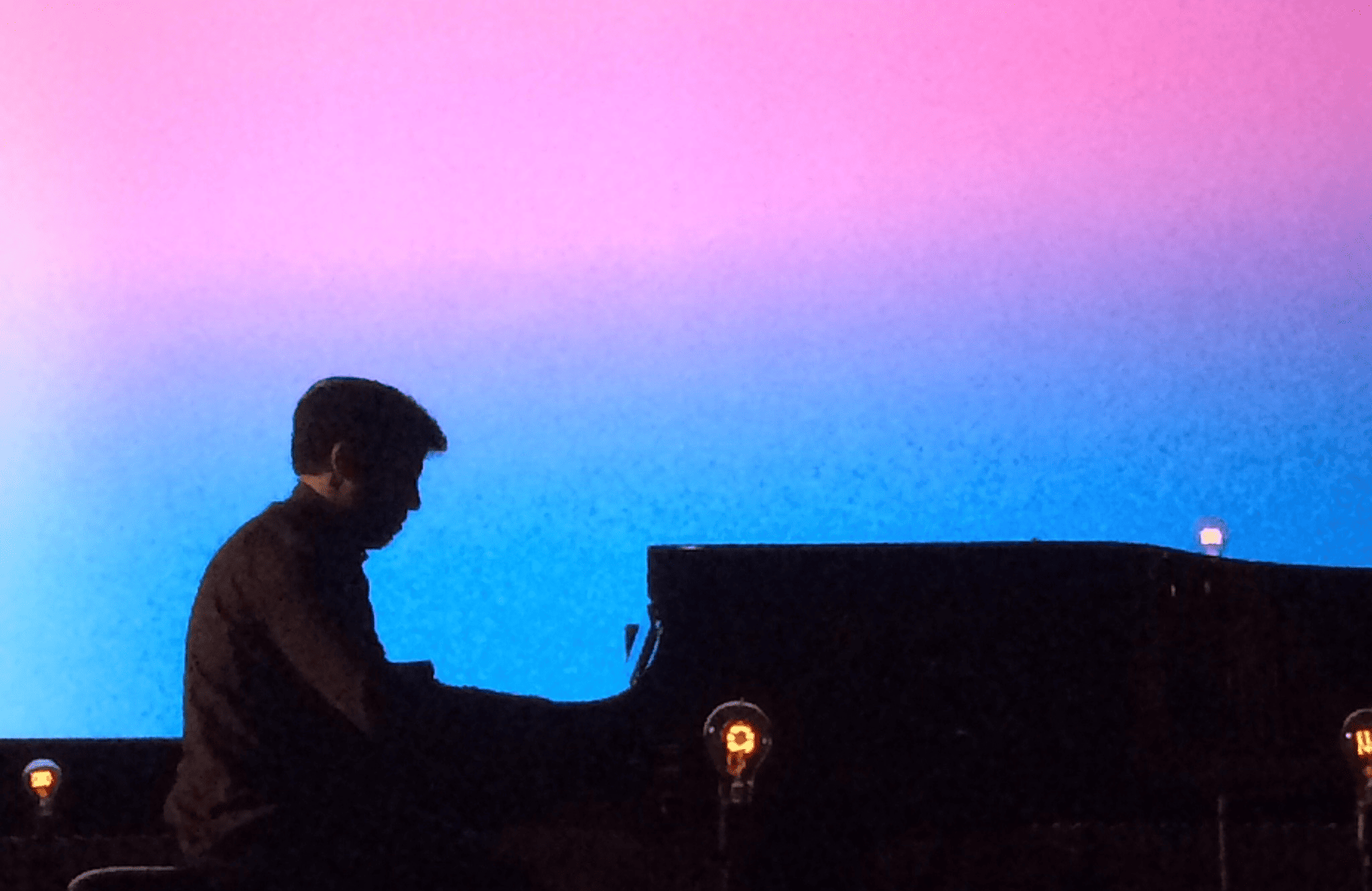 person playing a piano on a stage with a colorful