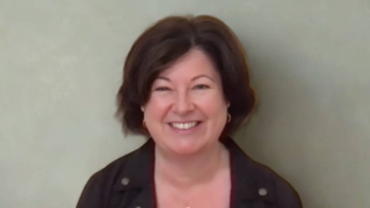 Maria Furlano headshot smiling with gray green background