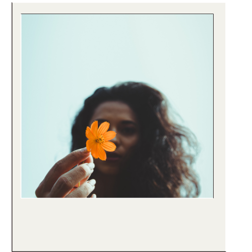 out of focus picture of a woman holding an orange flower