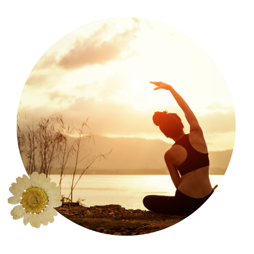 woman, back to camera. Performing a stretch on the ground facing a river.