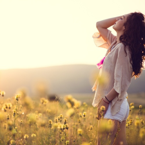 Woman in field of flowers, she has her hand running through her hair.