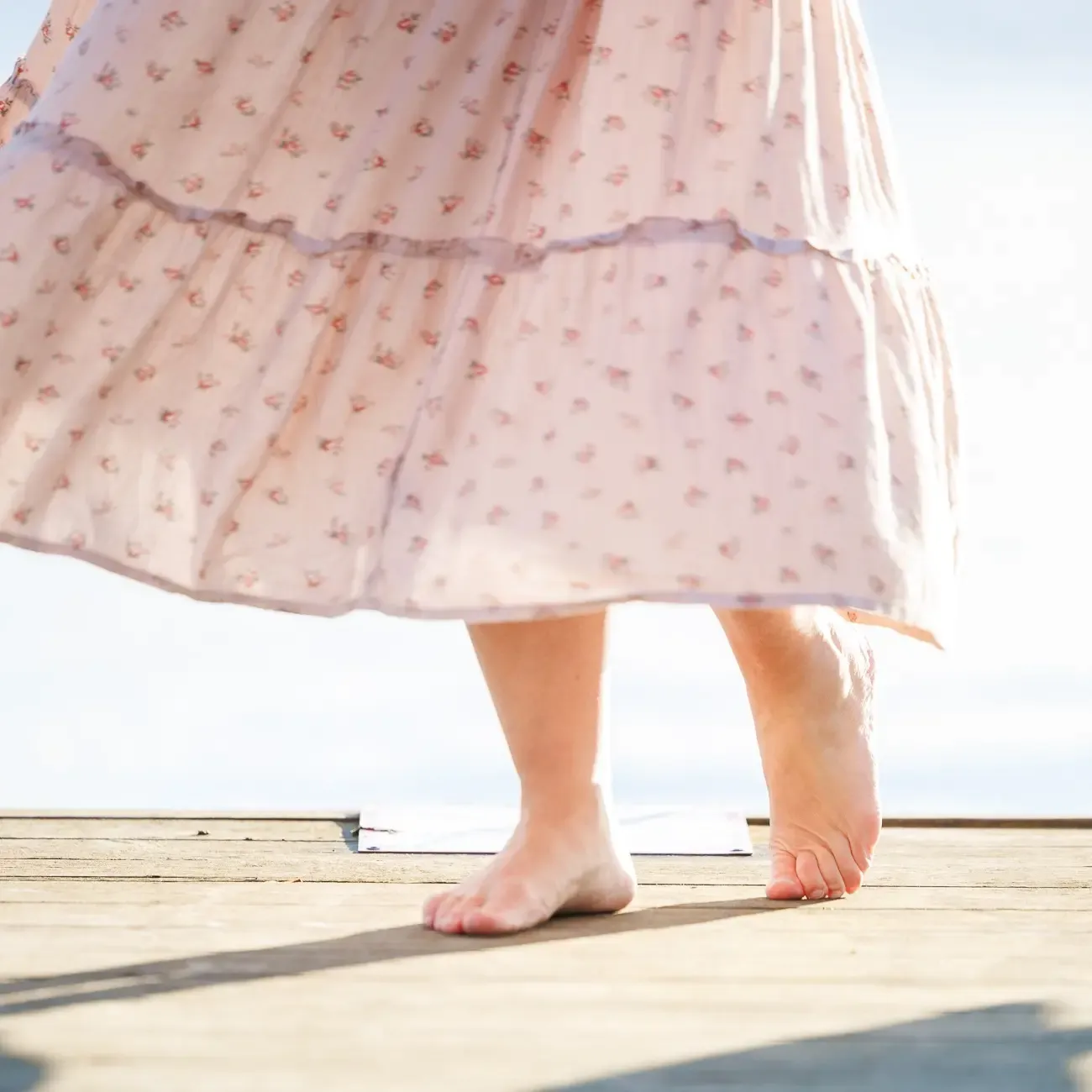 Woman standing on a yeti. You can only see her skirt and feet. She is walking towards us and the wind is gently blowing the skirt.