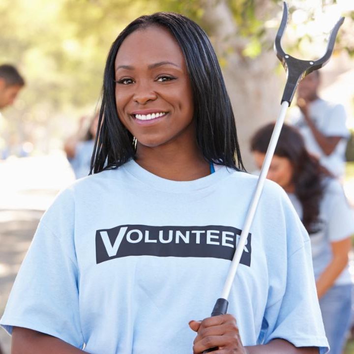 Young Black women with a shirt that reads volunteer, holding a grabber.