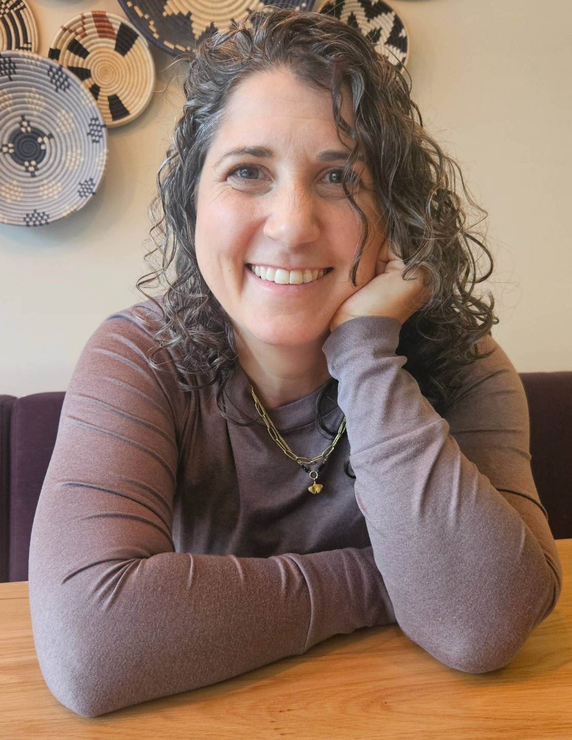 Laura Baringer, business coach for purpose-driven entrepreneurs, smiling at a workspace.