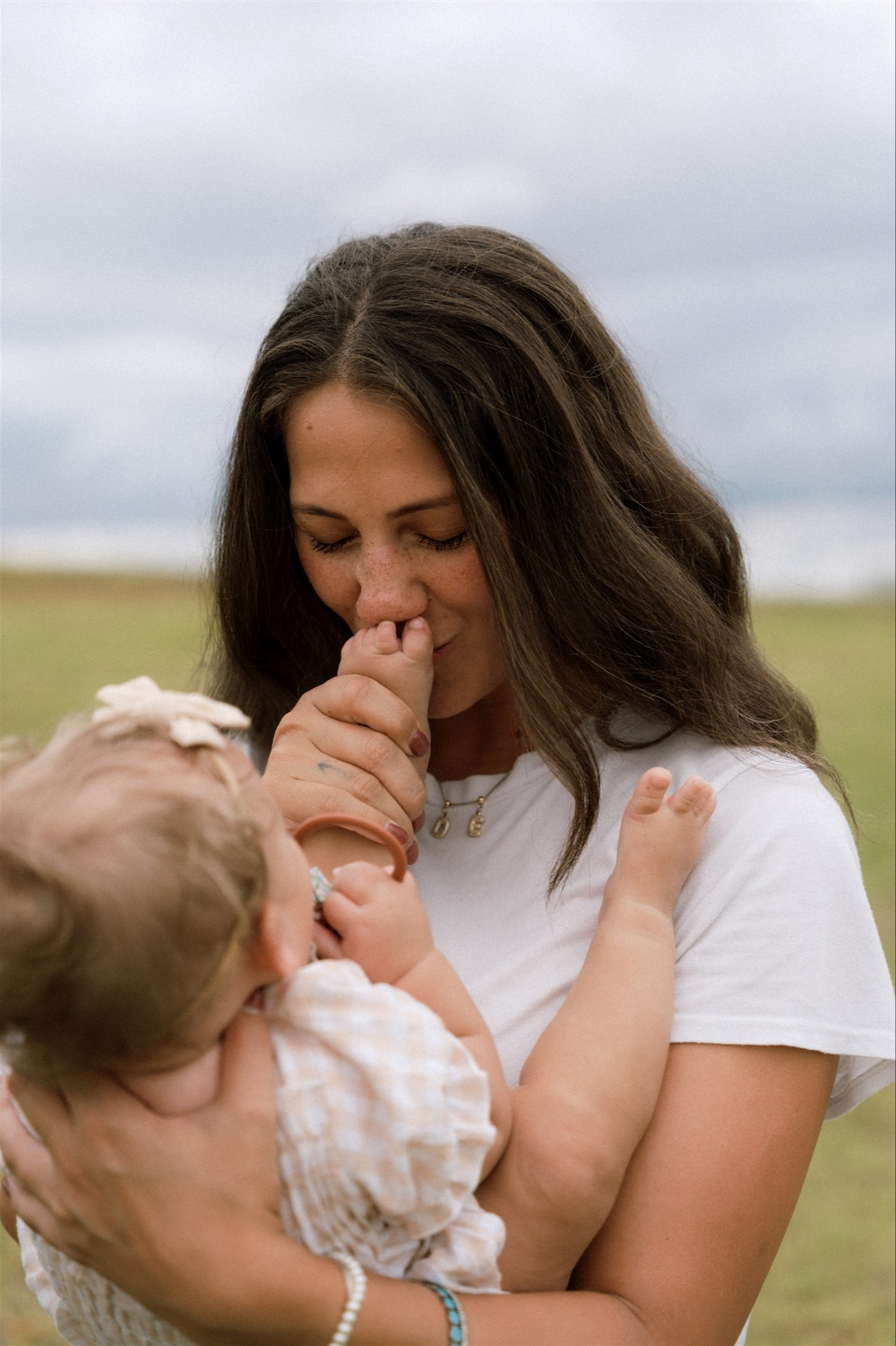 Tender moment of a parent kissing their baby's foot beneath the words "Notice. Nurture. Thrive" - symbolizing holistic family wellness and care.