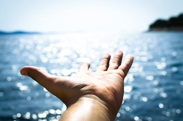 A hand reaching out over sparkling water