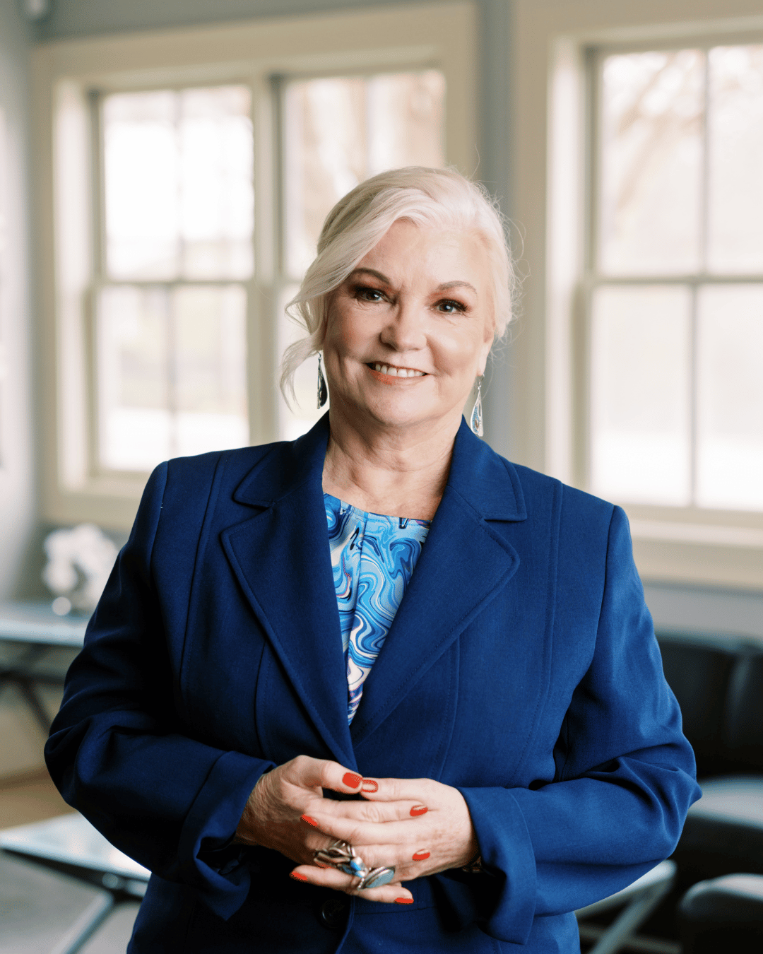 Debbie with glasses and arms folded facing camera.