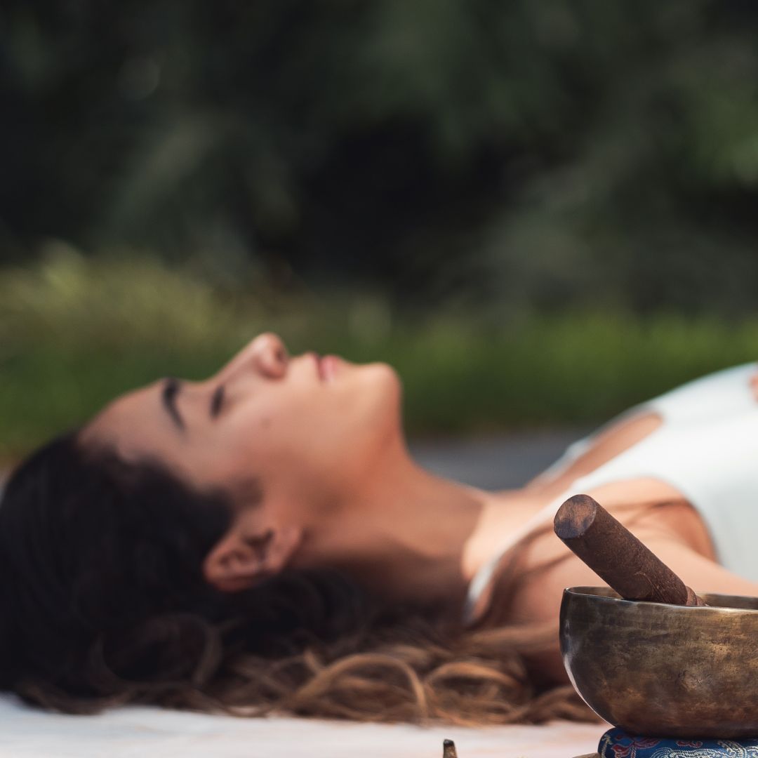 woman on yoga mat with singing bowl with crystals