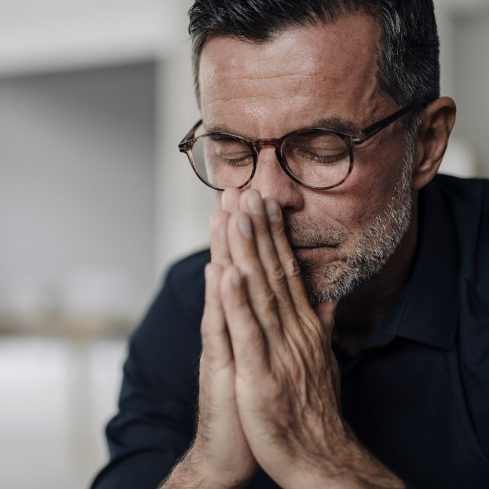Man with closed eyes and hands to face looking worried