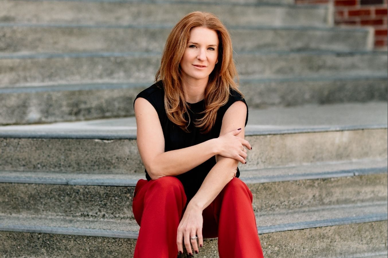 Rebecca Kase, founder of the Trauma Therapist Institute, seated on a couch wearing a pink top
