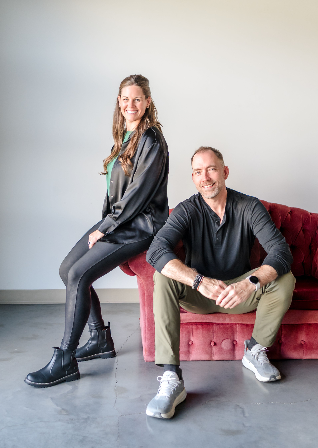 Danielle Grant (Your Mindset Mentor) & Trevor Turnbull (Elevated CEO) sitting on a pink couch, power poses, and smiling