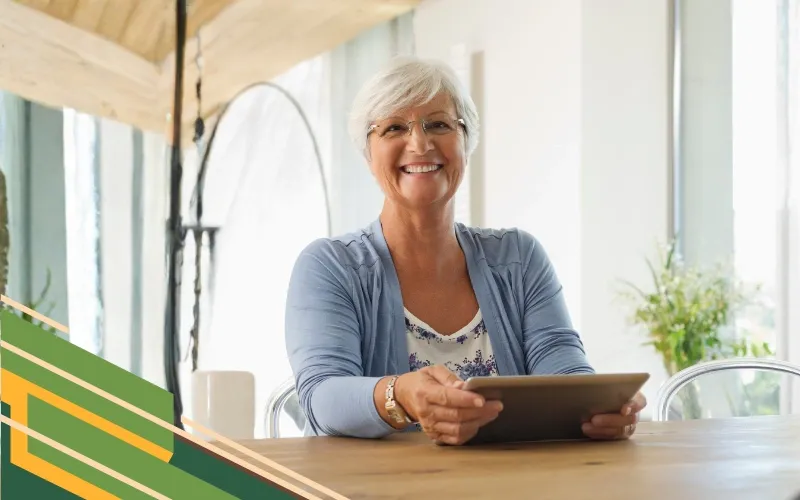 Elderly woman in a pink lace dress with outstretched arms, smiling wide and looking upwards, against a peach-colored background.