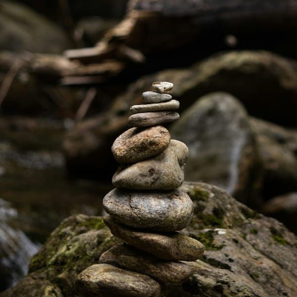 Stacked balanced stones near water representing mindset, focus, and stability.