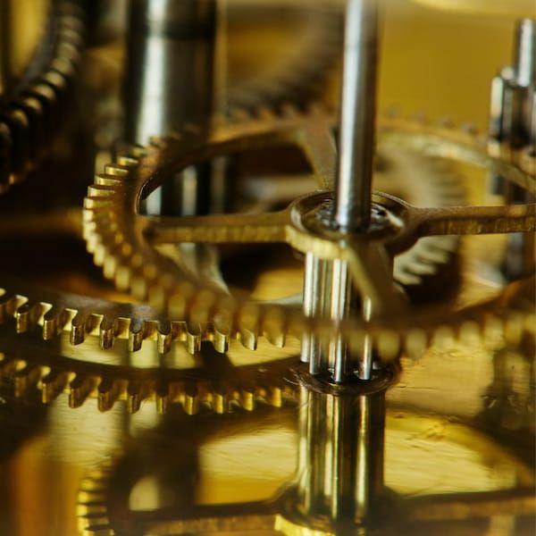Close-up of intricate interlocking brass gears representing business systems and processes.