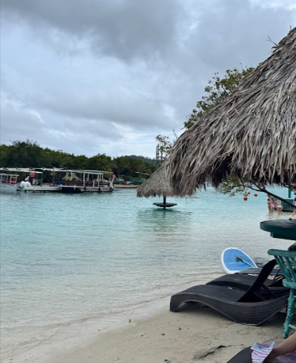 Little French Key Roatan: Thatched beach hut and lounge chairs beside clear shallow water
