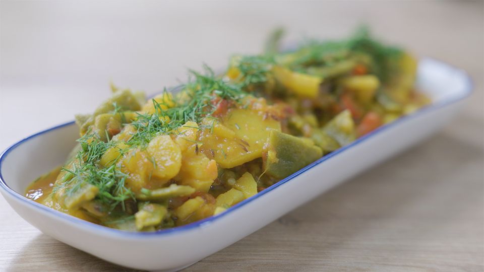 Ayurvedisches Grüne-Bohnen-Kartoffelcurry mit Kreuzkümmel und frischem Dill auf weißem Teller