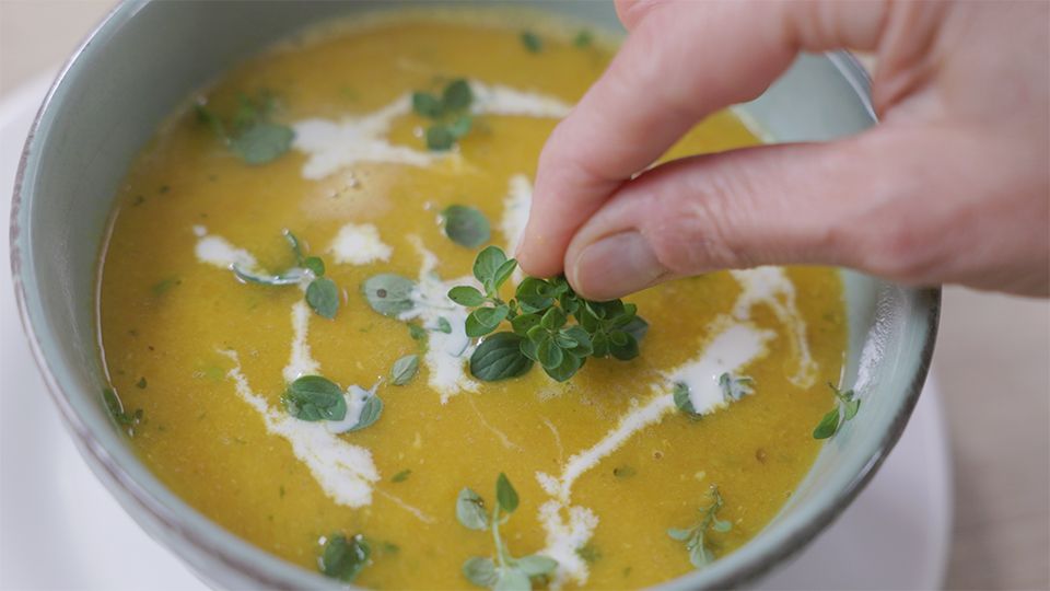 Ayurvedische Dal-Tomatensuppe mit Zimt, Kokosmilch und frischem Thymian in grauer Keramikschale