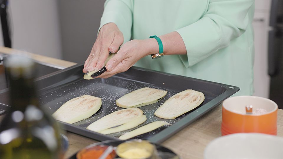 Auberginen mit Himalaya-Salz einreiben – ein einfacher, aber wichtiger Schritt. Das Salz entzieht der Aubergine Bitterstoffe und bereitet sie für die sanfte Zubereitung im Ofen vor.