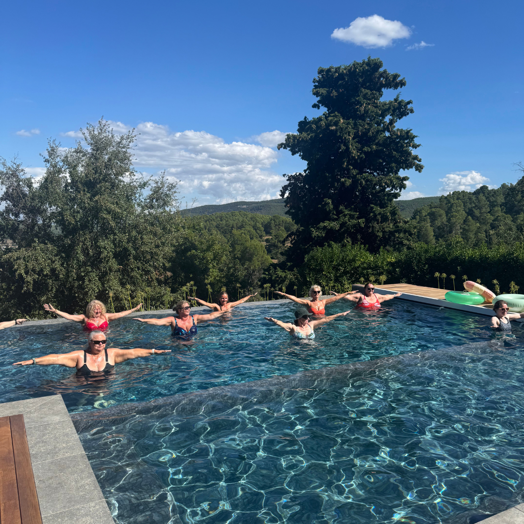 Female practicing aquafit holds hand weights in outdoor pool at Yourself Yoga’s menopause wellness retreat near Barcelona