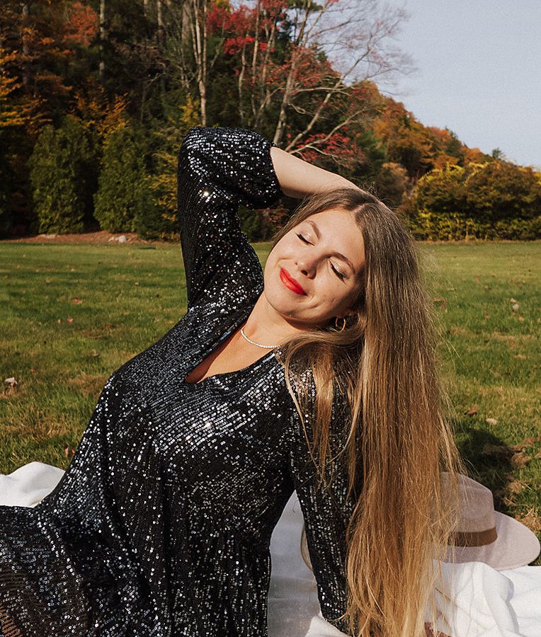 woman with her hand on her head, sitting down, looking blissful
