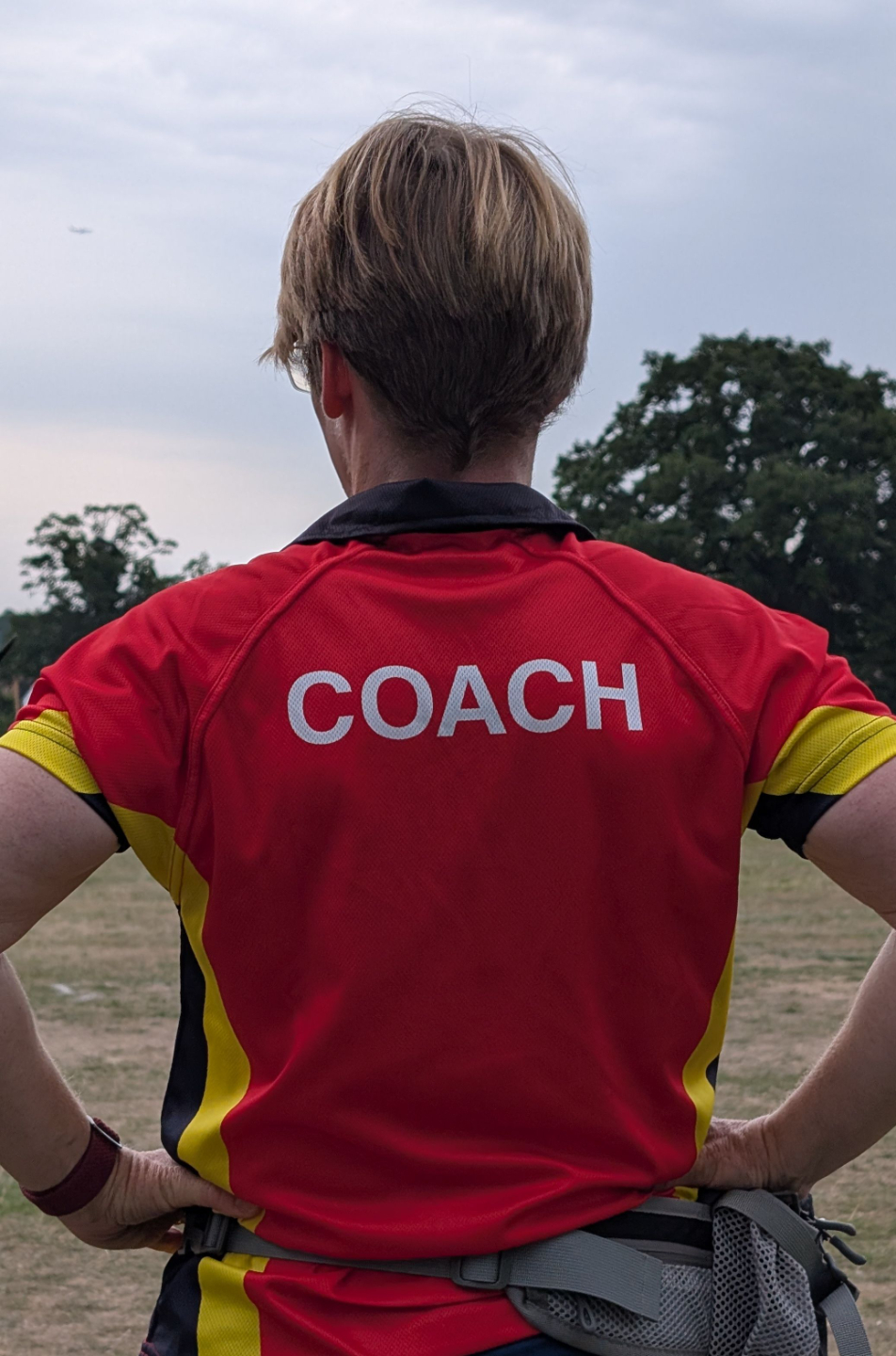A photo of the back of Becky Steliaros wearing her "coach" archery t shirt