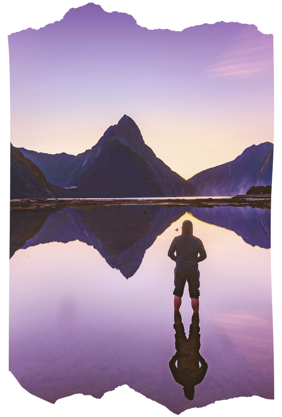 Silhouette of a person standing before a calm mountain lake at sunrise, reflecting the unseen and spiritual realms.