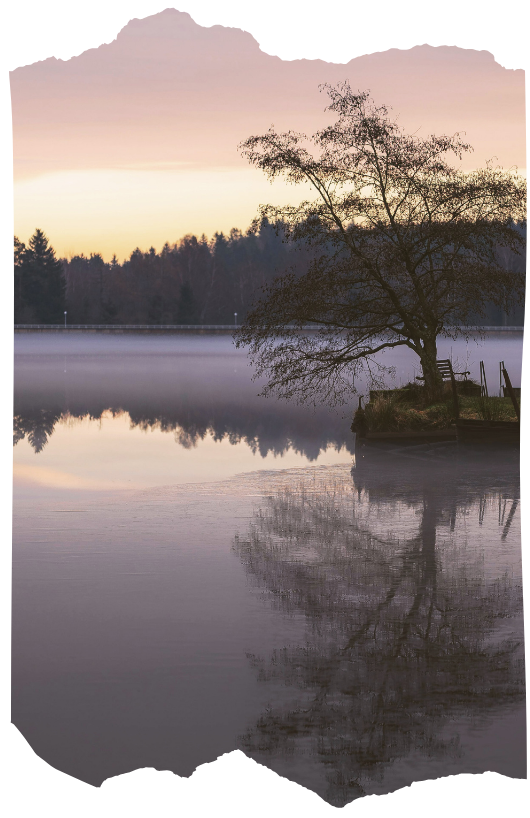 Silhouette of a person standing before a calm mountain lake at sunrise, reflecting the unseen and spiritual realms.
