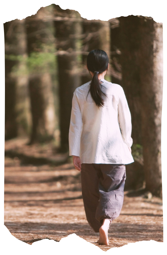 Person walking barefoot down a sunlit forest path, symbolizing beginning a grounded and confident shamanic journey.