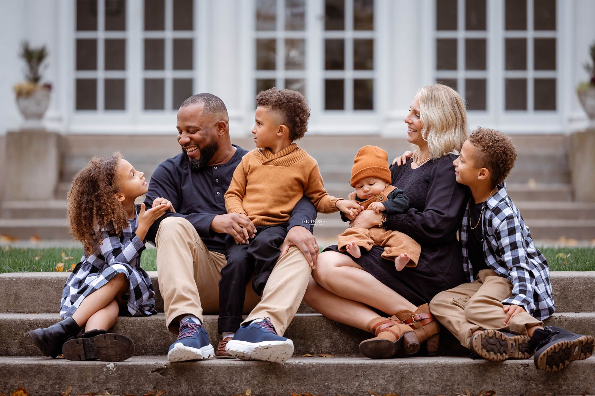 family sitting on steps looking at each other laughing