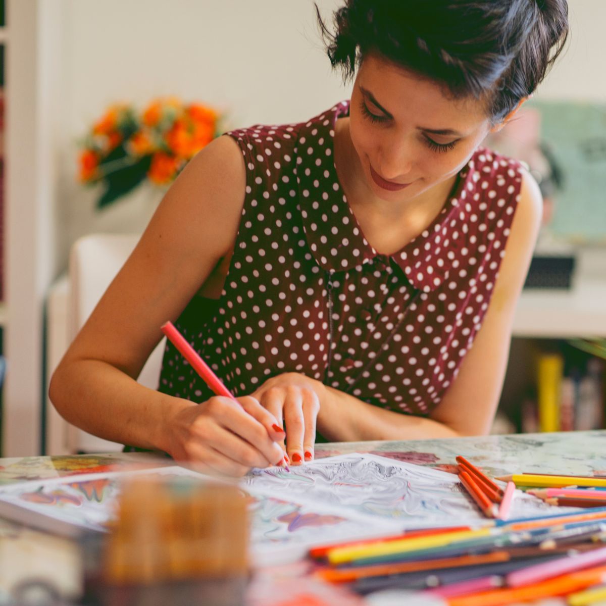 Woman at a table using colored pencils on a coloring sheet
