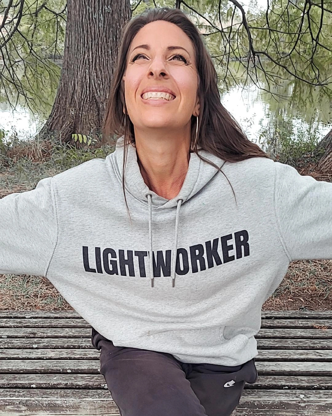 Spiritual teacher Emily Wehrman smiling with her arms out wearing a gray sweatshirt LIGHTWORKER.