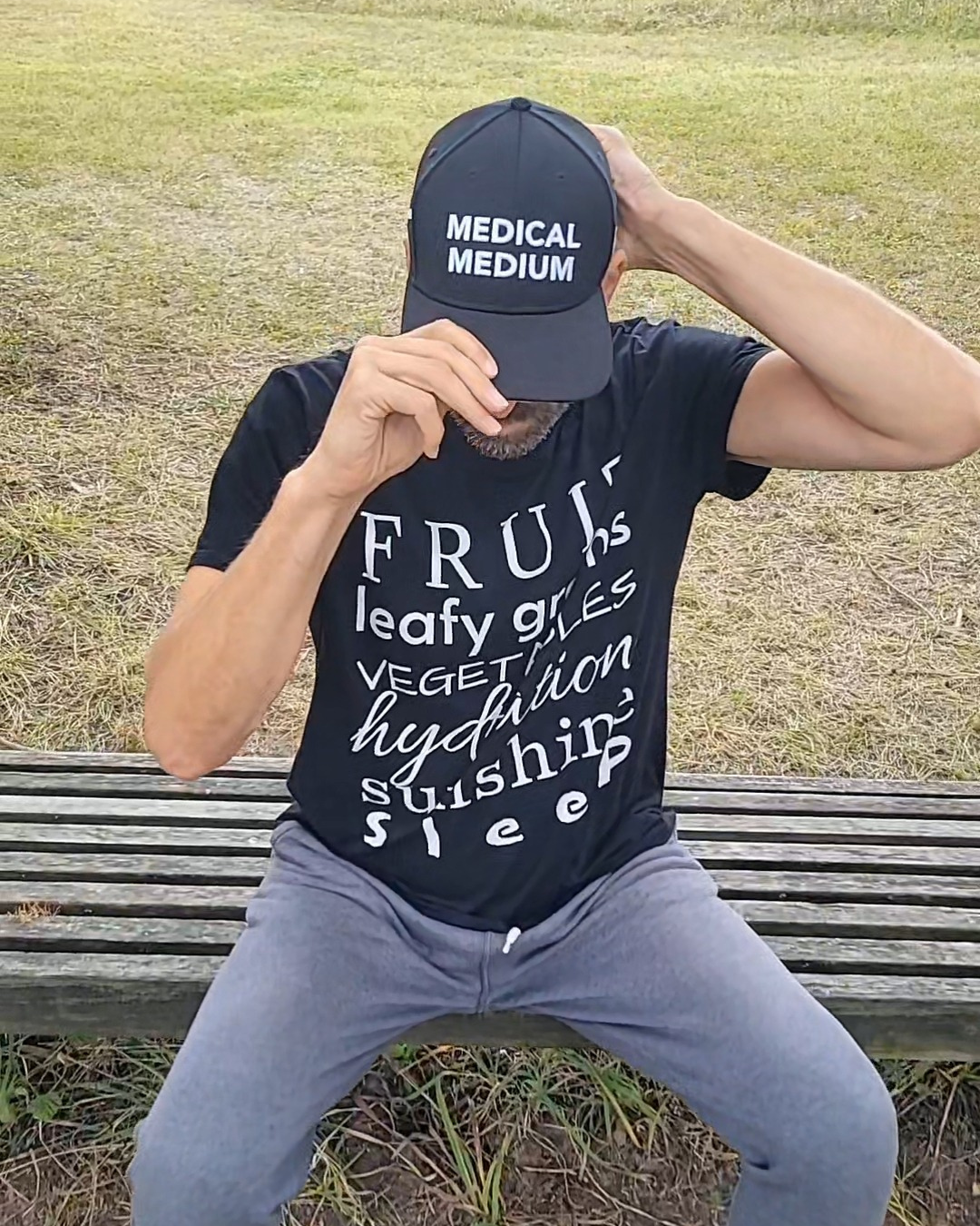 Man sitting on a bench wearing a black shirt with custom text from Emily Wehrman's shop EMpowered Designs.