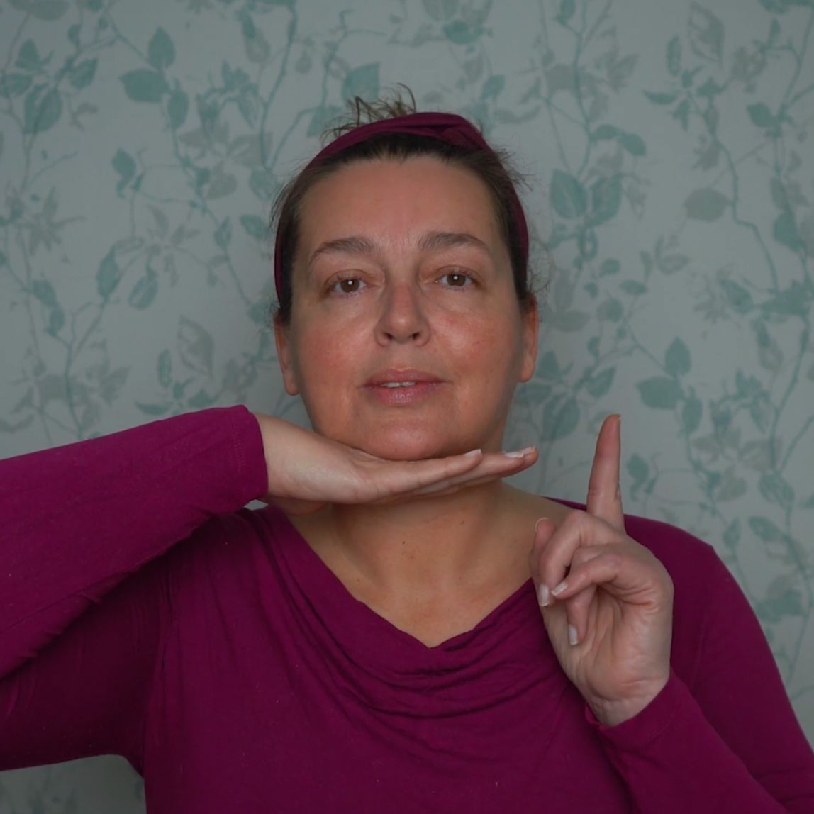 Face yoga teacher looking upward with a book balanced on her head
