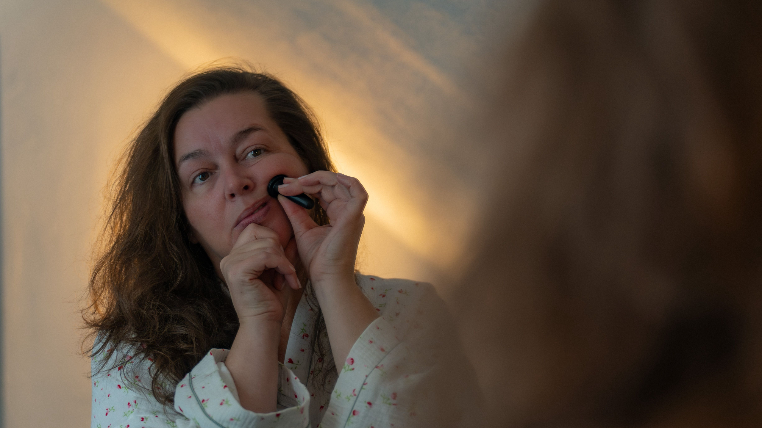 Face yoga teacher demonstrating a lifting face yoga exercise with fingers placed along the cheeks