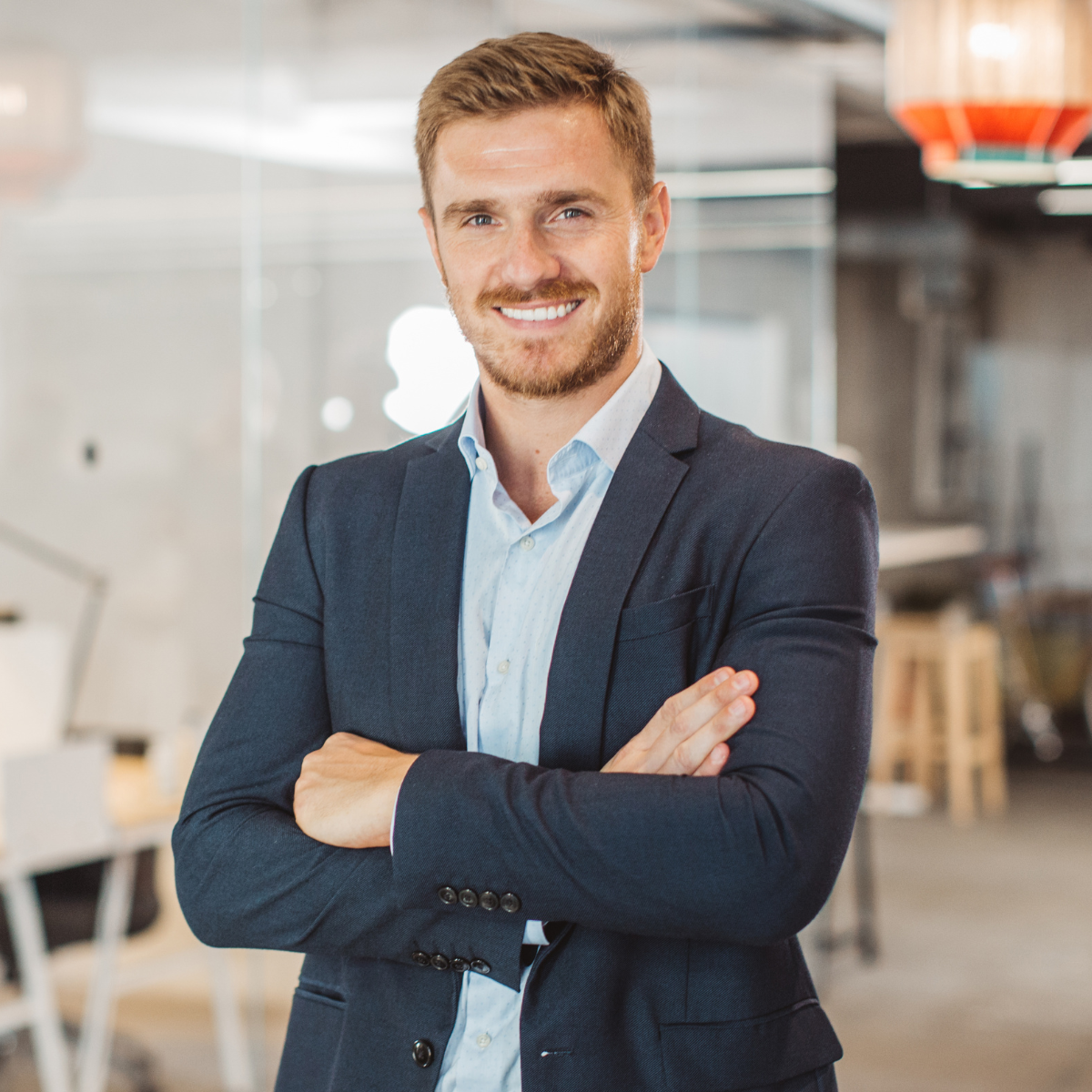 Professional man in a suit standing in an office smiling at the camera