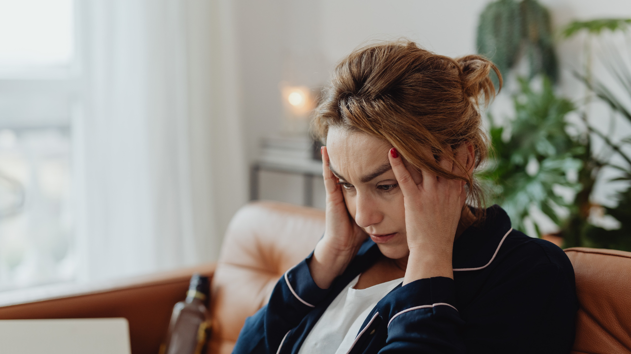 Woman upset sitting on the couch with her head in her hands